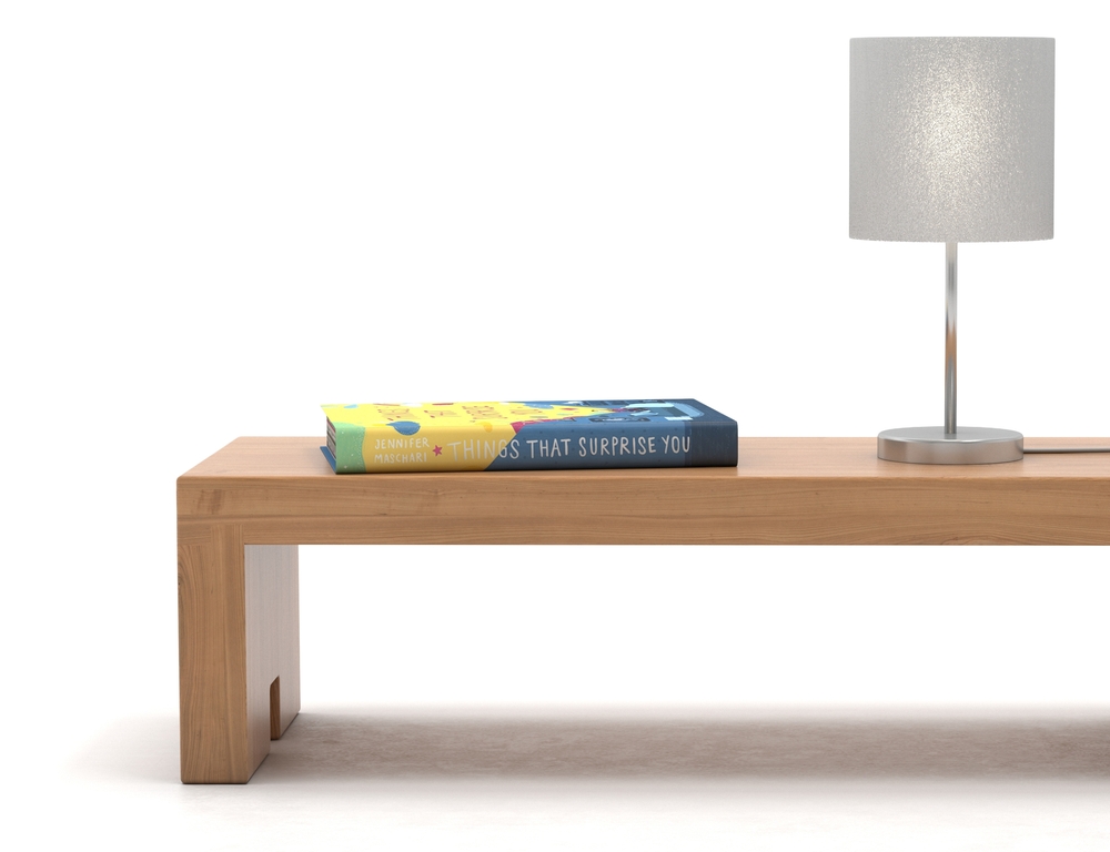 Banc en bois utilisé comme table de nuit, un livre et une lampe sur le dessus