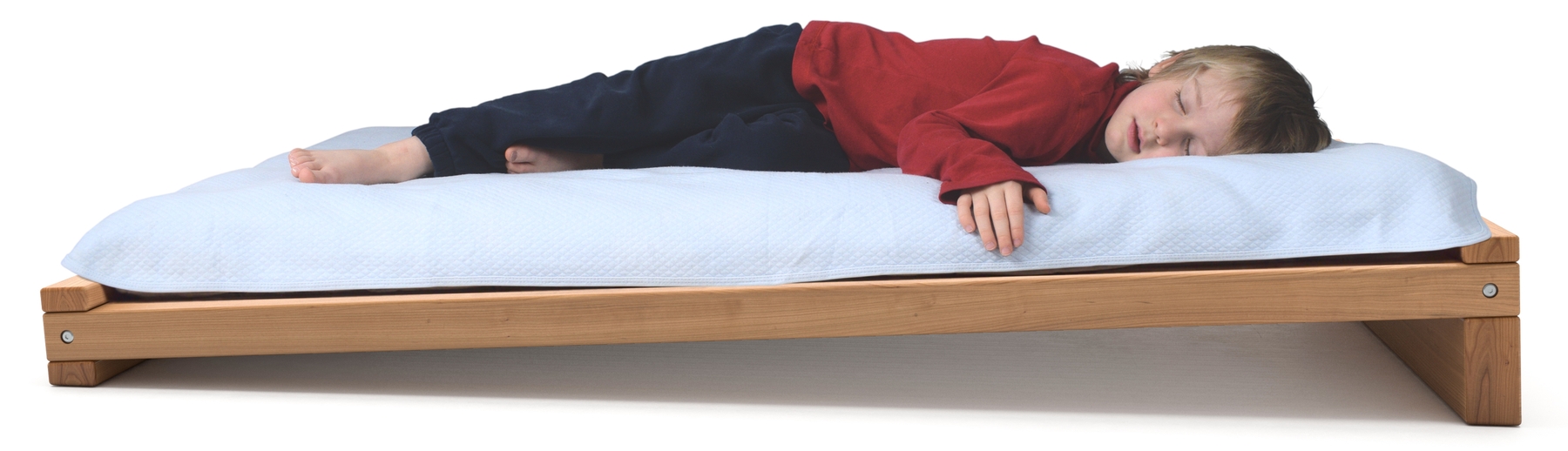Boy sleeping on an inclined Montessori toddler bed