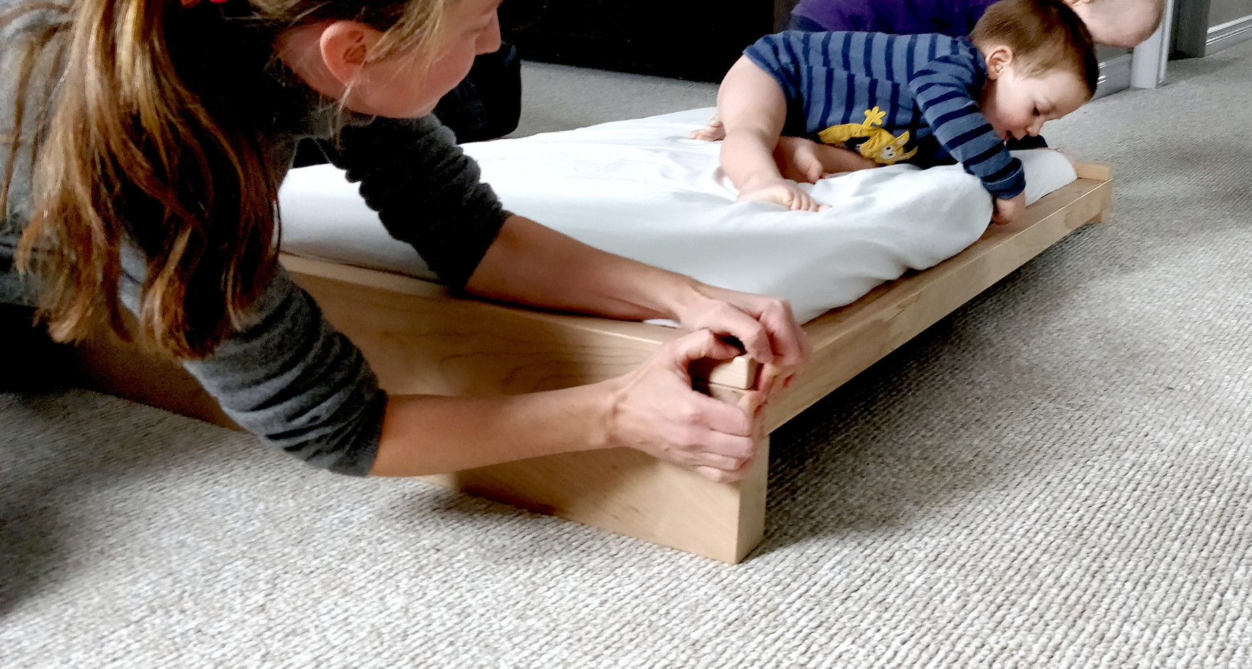 Assemblage d'un lit en bois massif, avec deux jeunes enfants aidant