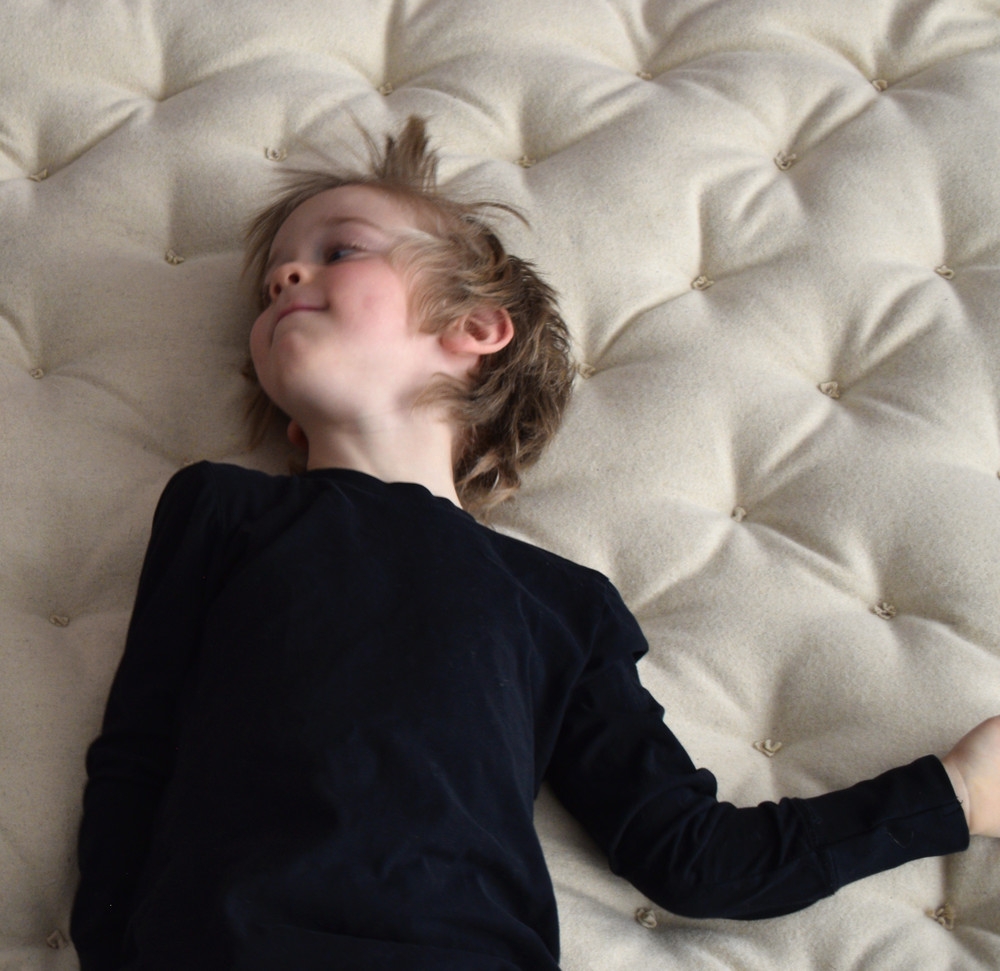 Garçon allongé sur un matelas en laine tufté